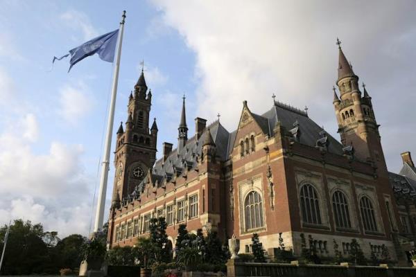 An exterior of a grand, old, brick palace with a United Nations flag flying out the front.