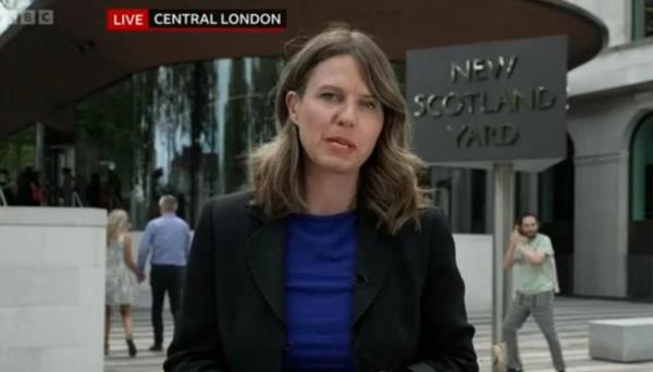 一名男子在苏格兰场的招牌下假扮詹姆斯·邦德，接受BBC关于性丑闻的现场采访