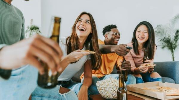 group of friends laughing over funny questions while eating popcorn and drinking beer